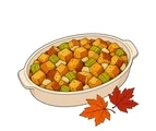 Oval casserole dish filled with golden stuffing beside two large colorful autumn leaves.